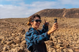 A young woman making a video next to the Crater of the Calderon Hondo volcano near Corralejo