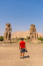 A young photographer visiting two Egyptian sculptures in the city of Luxor along the Nile. Egypt