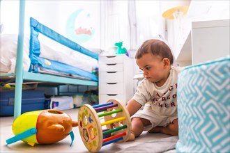 Young Caucasian mother playing with her in the room with toys. Baby less than a year learning the first lessons of her mother. Boy playing on the floor with toys