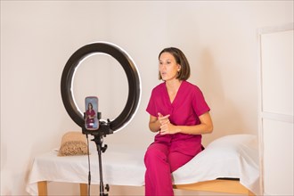 Horizontal photo with copy space of a specialist nutrition doctor records an online video at home using a ring light and a mobile phone