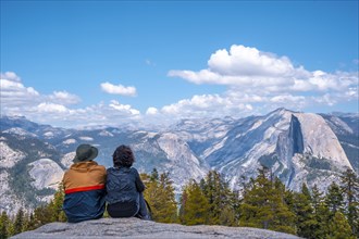 A couple sitting in Sentinel Dome looking at Yosemite National Park. United States