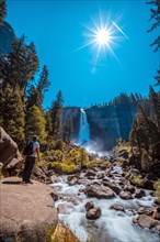 A European tourist with a white T-shirt in Vernal Falls from the bottom looking at the waterfall. California