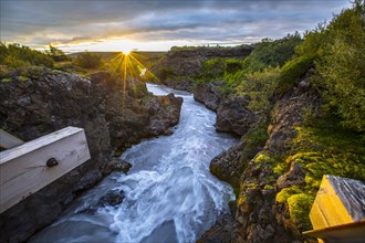 Gorgeous sunset on the wooden bridge of the Barnafoss river