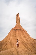 Brunette Caucasian girl with a white dress and a straw hat in the Castildetierra of the Bardenas Reales desert