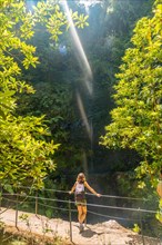 A young woman looking at a small waterfall in summer on the Levada do Caldeirao Verde