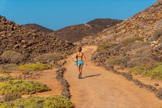A young woman with a blue bikini on the trail to the north of the Isla de Lobos