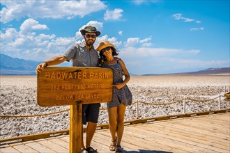 A couple tourists walking white salt of Badwater Basin