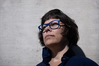 Headshot on a Elegant Woman with Eyeglasses and Leaning on a Concrete Wall in a Sunny Day in Switzerland