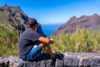 A tourist with a cap looking at the mountain municipality of Masca in the north of Tenerife