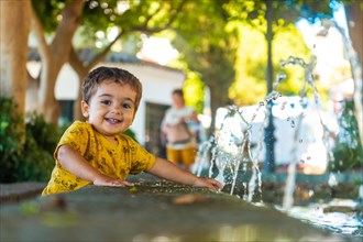 A smiling baby cooling off from the heat in the fountain in the municipality of Mijas in Malaga. Andalusia