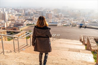 A young tourist walking in the viewpoint of Cerro San Cristobal and the city of Almeria in the background