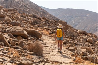 A hiker with a yellow backpack walking along the canyon path towards the Mirador de la Penitas
