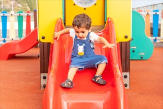 Boy playing in a playground having fun in summer and getting off the squeaker