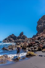A young tourist enjoying summer by the sea on some rocks in Playa de Nogales in the east of the Island of La Plama