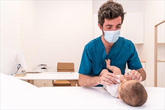 Photo with copy space of a doctor examining a newborn baby lying on a stretcher in a clinic