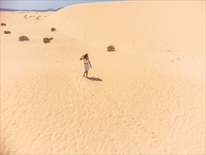 A young woman walking through the sand in the dunes of the Corralejo Natural Park