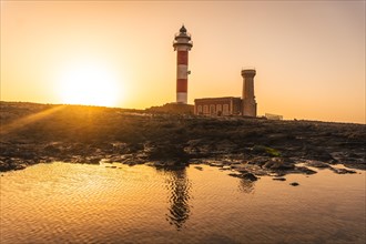 Sunset at the Toston Lighthouse near the sea with the reflected lighthouse