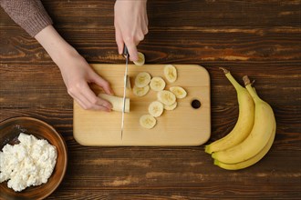 Unrecognizable person cutting banana slices