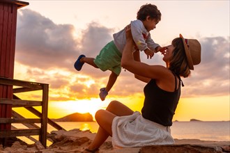 Mother having fun with her son at sunset in Cala Comte beach on the island of Ibiza. Balearic