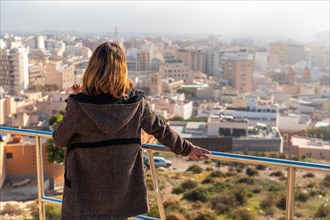 A young tourist girl looking at the city from the viewpoint of Cerro San Cristobal in the city of Almeria