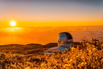 Large Canary Telescope called Grantecan optico del Roque de los Muchachos in the Caldera de Taburiente in a beautiful orange sunset
