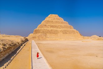 A young woman in a red dress visiting the Stepped Pyramid of Djoser