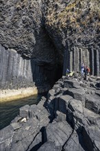 Tourists at the entrance to the 80 metre long and 10 metre wide Fingal's Cave on the uninhabited rocky island of Staffa