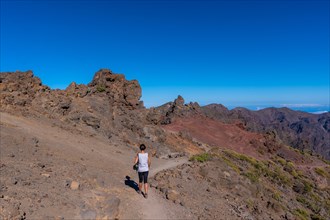 A young woman walking atop the Caldera de Taburiente volcano near Roque de los Muchachos one summer afternoon