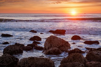 Atlantic ocean sunset with waves and rocks at Costa da Caparica