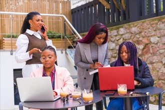 Young businesswomen of black ethnicity. At a business meeting in a cafeteria with computers and coffee on the table. Teamwork