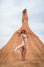 Brunette Caucasian model in a white dress and straw hat in the Bardenas Reales desert