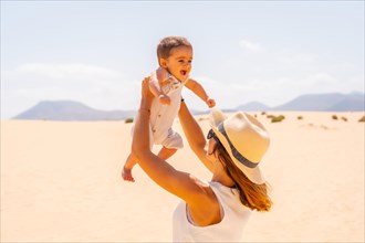 Young mother having fun with her son on vacation in the dunes of Corralejo Natural Park