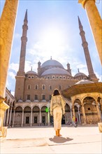 A young tourist walking in the inner courtyard of the Alabaster Mosque and the gigantic pillars in the city of Cairo