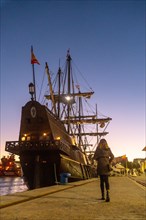 A tourist visiting the old ship at sunset on the promenade of Muelle Uno in the Malagaport of the city of Malaga