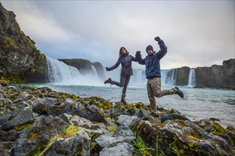A young couple tourist looking at the Godafoss waterfall from above. Iceland