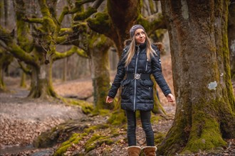 A happy young woman in a tree in the Otzarreta Forest in the natural park of Gorbea