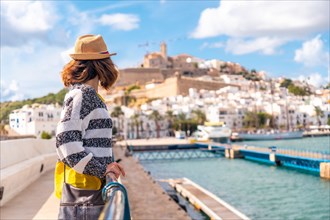Young woman visiting coastal Ibiza town on vacation from Al Faro