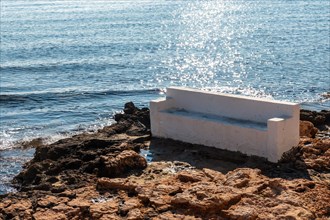 A white seat by the sea in the coastal town of Torrevieja next to Playa del Cura