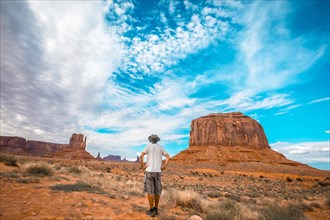 Man with white t-shirt and green hat in the Monument Valley National Park in Three Sisters. Utah