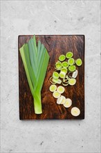 Top view of fresh leeks on wooden cutting board