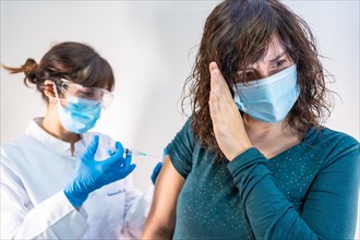 A woman doctor with a face mask applying the coronavirus vaccine
