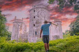A young tourist visiting the medieval Hunaudaye Castle at sunset