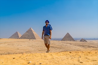 Portrait of a young man in a blue turban walking next to the Pyramids of Giza