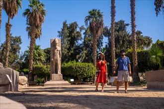 A tourist couple visiting the sculpture of Pharaoh Ramses II at Memphis in Cairo