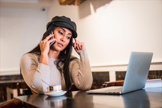 Latina brunette architect making a work call with a laptop from a coffee shop
