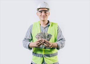 Portrait of happy engineer in helmet holding money isolated. Cheerful male engineer holding money on isolated background