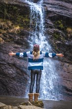 A young straight-haired blonde in a blue and white wool sweater in a beautiful waterfall. Lifestyle session