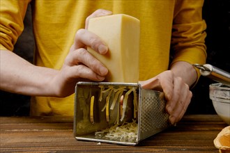 Unrecognizable man shredding cheese with metal grater
