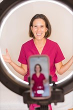 Vertical photo of a female doctor nutritionist recording a video blog with the mobile