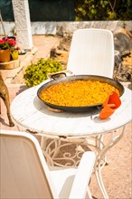 Valencian paella made on wood embers and vegetables on the restaurant table. Traditional Spanish Mediterranean food of fish and seafood